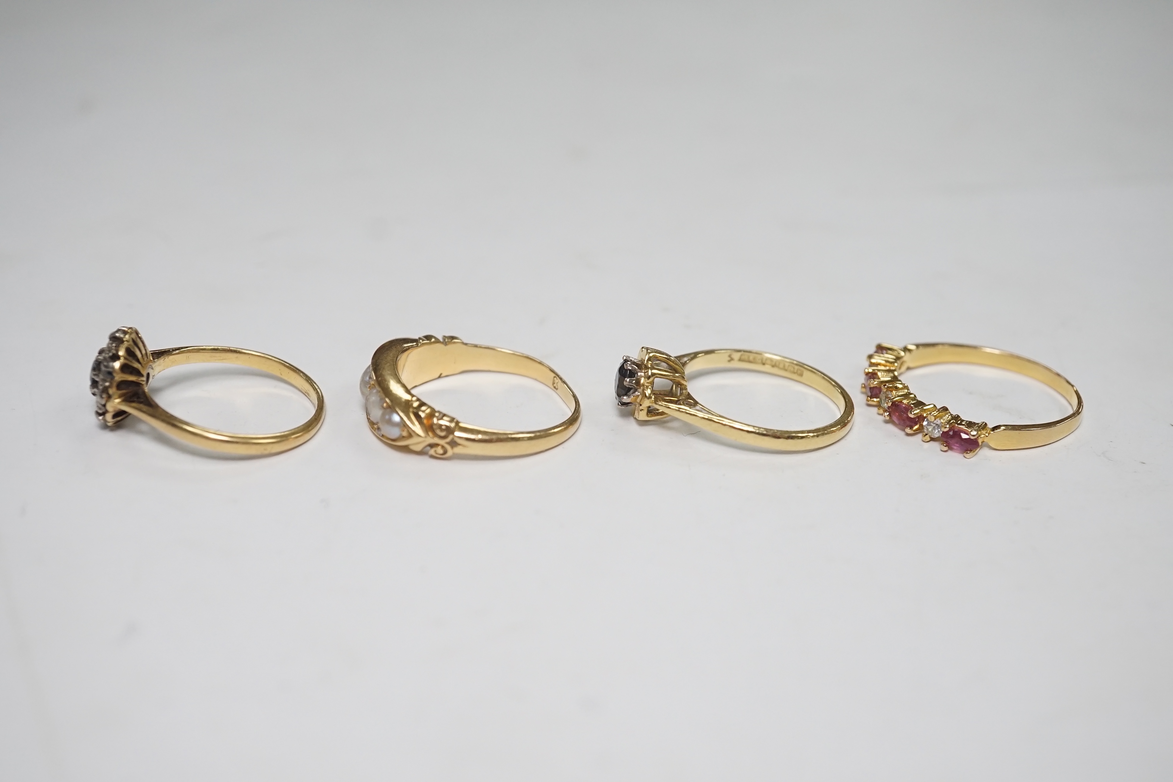 A late Victorian yellow metal and five stone split pearl set half hoop ring, with diamond chip spacers, size N/O, two modern 18ct gold and gem set rings and one other ring. Condition - fair to good